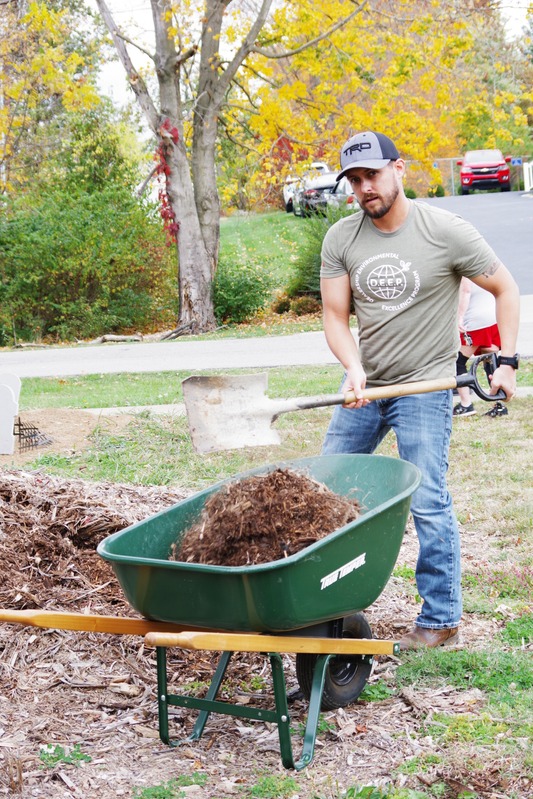 Swope employee moving mulch during a community garden project