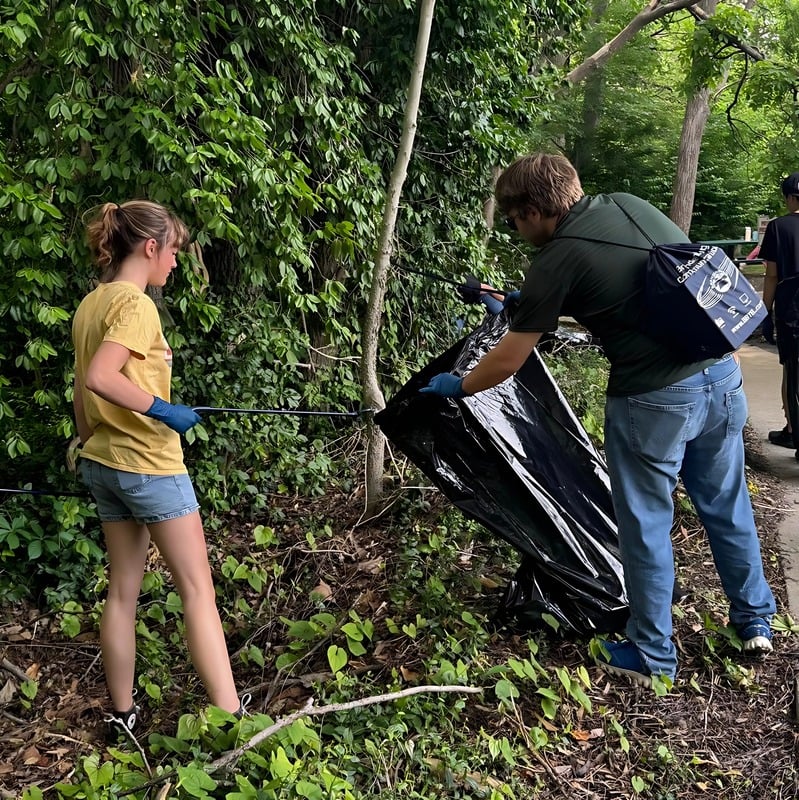 Volunteers collecting litter beside a wooded creek